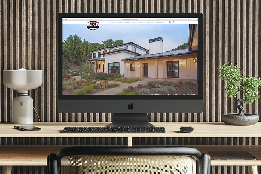 The JRP website is displayed on an iMac in designer surroundings