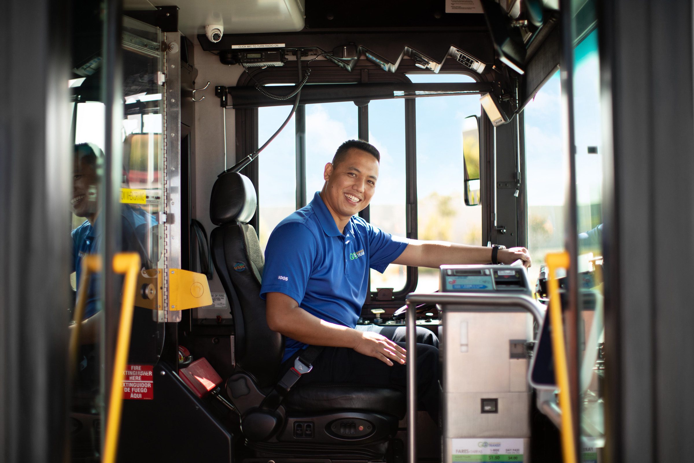 A Gold Coast Transit driver smiles broadly from the drivers seat for a photo
