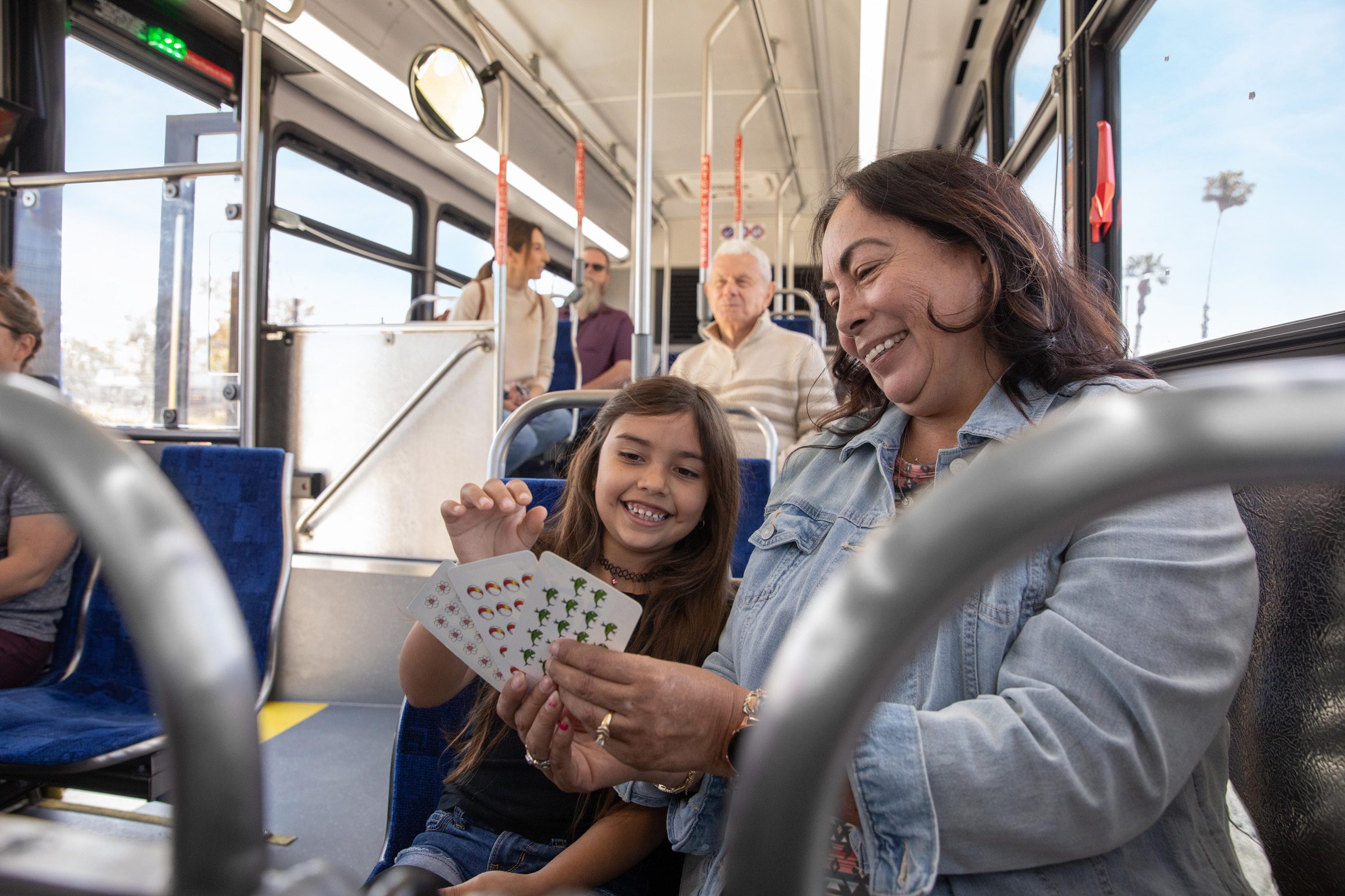 A woman and girl play cards while they sit on the bus
