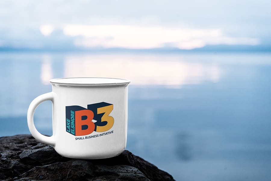 LEED_Portfolio_00 A white mug with a B3 Small Business Initiative logo sits on a rock by the calm, expansive waters of Lake Elsinore.