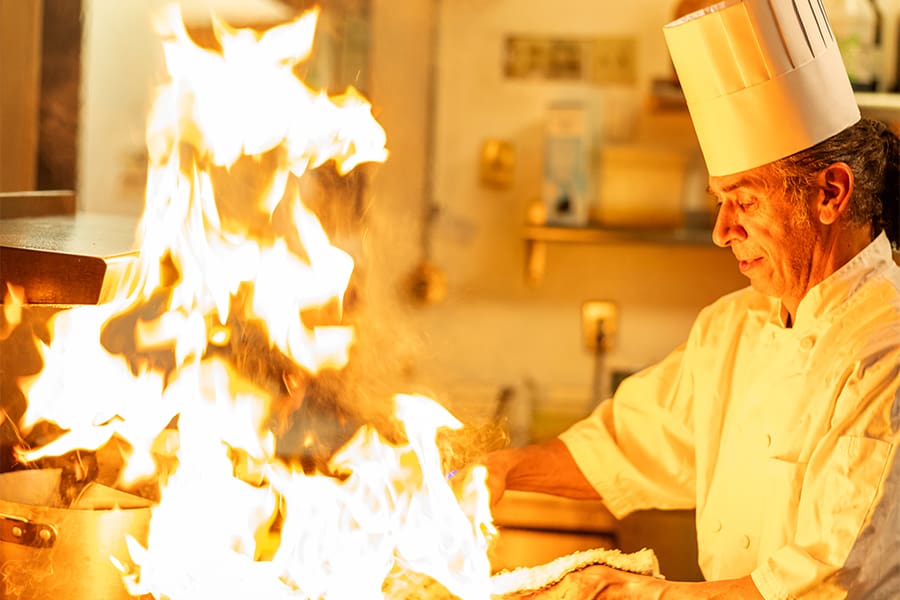 In a bustling kitchen in Lancaster, a chef in a crisp white uniform and hat expertly cooks over a stove, large flames dancing artfully before him. Capturing this culinary magic offers an exciting opportunity for video & photography enthusiasts.