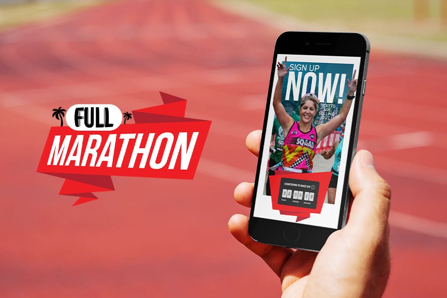 A hand holding a smartphone displaying a marathon sign-up screen, with Full Marathon on the left. The blurred background features a running track stretching towards majestic mountains, blending adventure with endurance.
