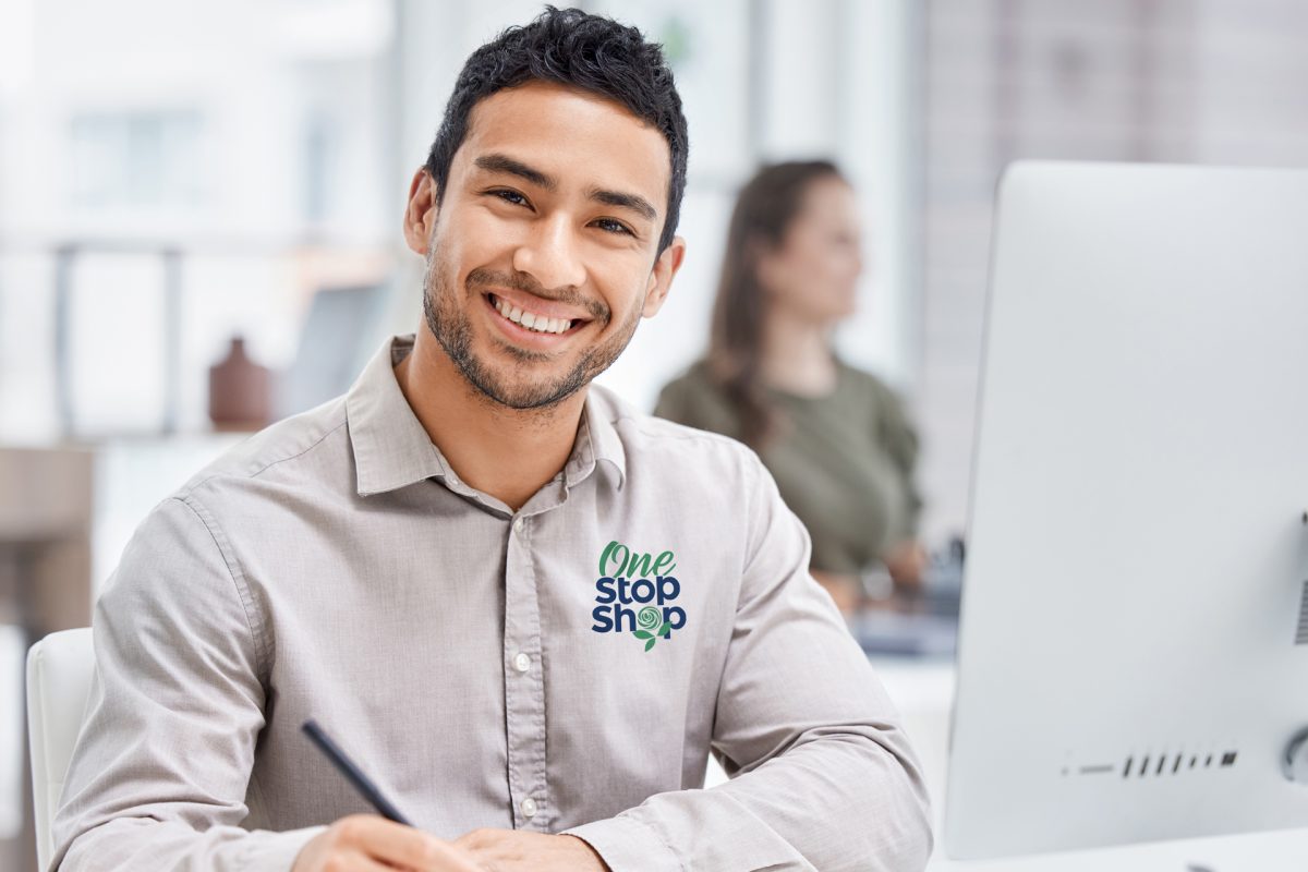 Smiling man at a desk with "One Stop Shop" logo, professional office environment.